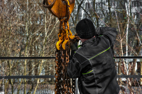 Tableau sur toile The rigger worker fixes the chain on the crane hook