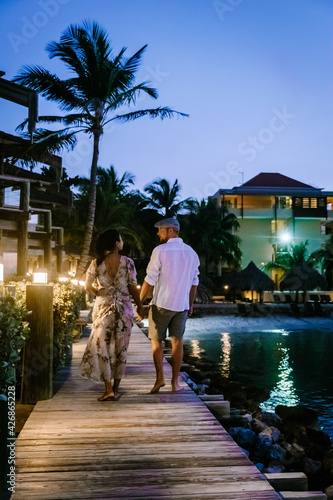 Curacao Willemstad, couple mid age Asian woman and European man on vacation at a luxury resort in Pietermaai , men and woman on the beach watching sunrise with beautiful orange pink sky photo