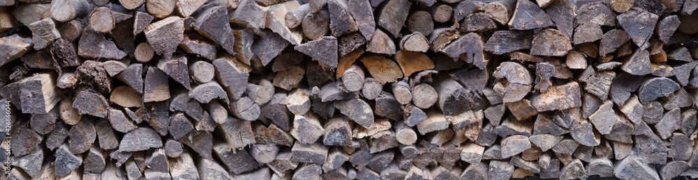 Wide view of stacked irregularly split logs for a stove, fireplace or wood stove