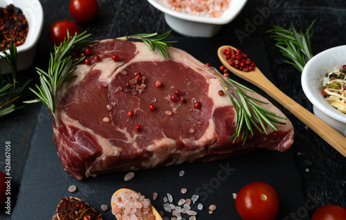 Raw ribeye steak beef fillet. Close-up meat with spices, salt and rosemary. An appetizing piece of meat. Holiday preparations