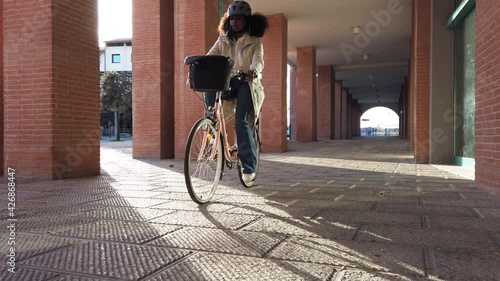 Commuter woman in city in sustainable way wearing bike helmet with protective face mask against Coronavirus Covid-19 pandemic rides her bicycle on way home to work - Slow motion