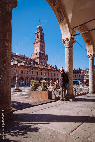 Man from behind leaning on column in the square of the Cathedral of Sant'Ambrogio (Duomo di Vigevano)