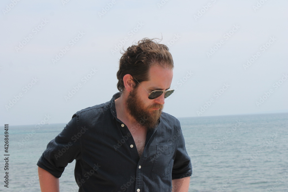 portrait of attractive man 30s with beard ocean sea behind him on sunny day portrait of attractive man 30s with beard ocean sea behind him on sunny day