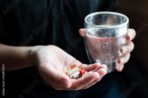 Wallpaper Mural Close-up of hand holding many pill that difference of color and shape and other hand holding glass of water. Supplements or antibiotic concept. Torontodigital.ca