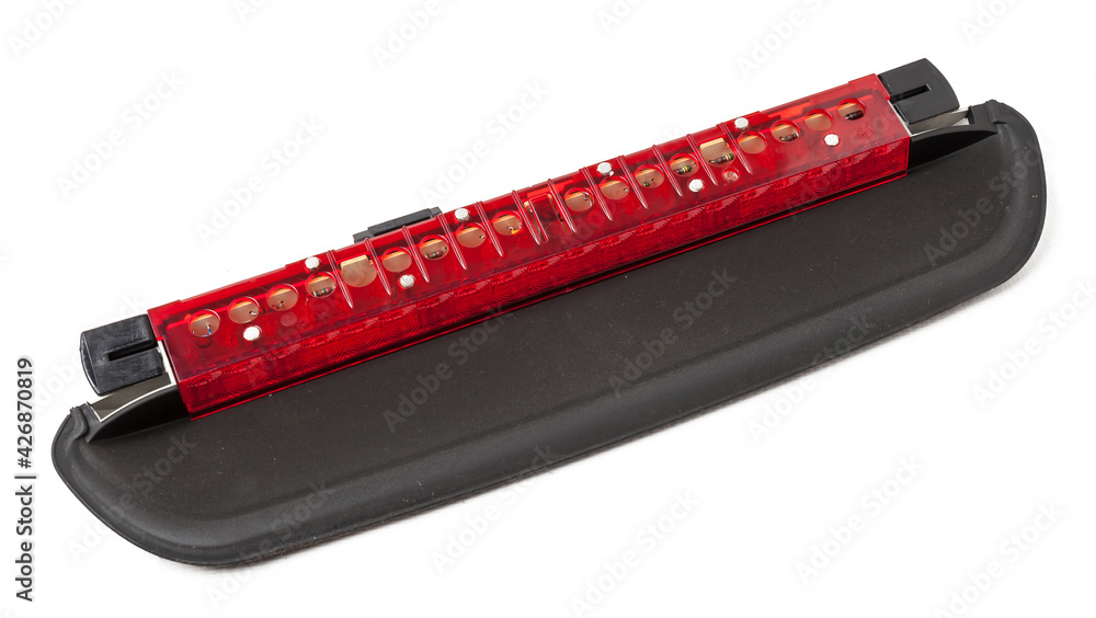 Spare part for sale at an auto-parsing or repair of a car body in service on a white isolated background in a photo studio - LED additional brake light from black and red plastic. Spare part for sale at an auto-parsing or repair of a car body in service on a white isolated background in a photo studio - LED additional brake light from black and red plastic.