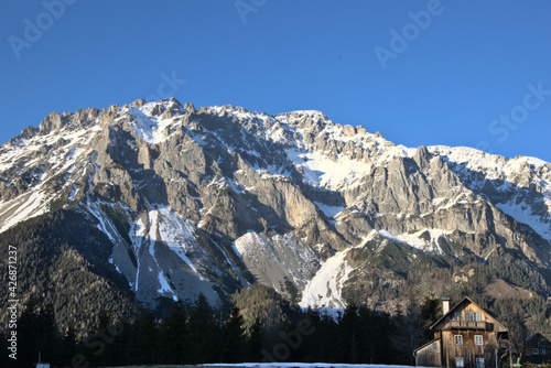 Wooden cabin in front of snowy mountains