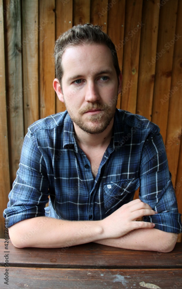 attractive male in blue plaid shirt against wooden fence background relaxed and confident portrait attractive male in blue plaid shirt against wooden fence background relaxed and confident portrait