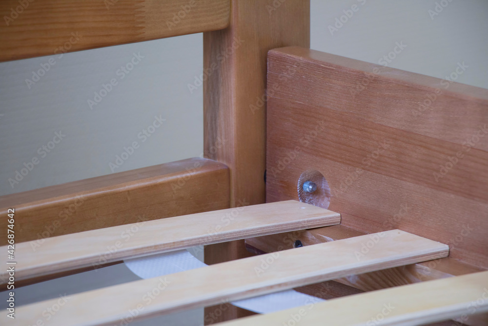 element of a double lacquered wooden bed with orthopedic slats and soft leather upholstery, close-up element of a double lacquered wooden bed with orthopedic slats and soft leather upholstery, close-up