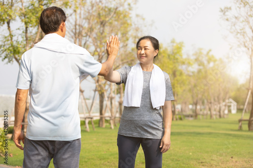 senior asian woman taking high five with hands after jogging in public park