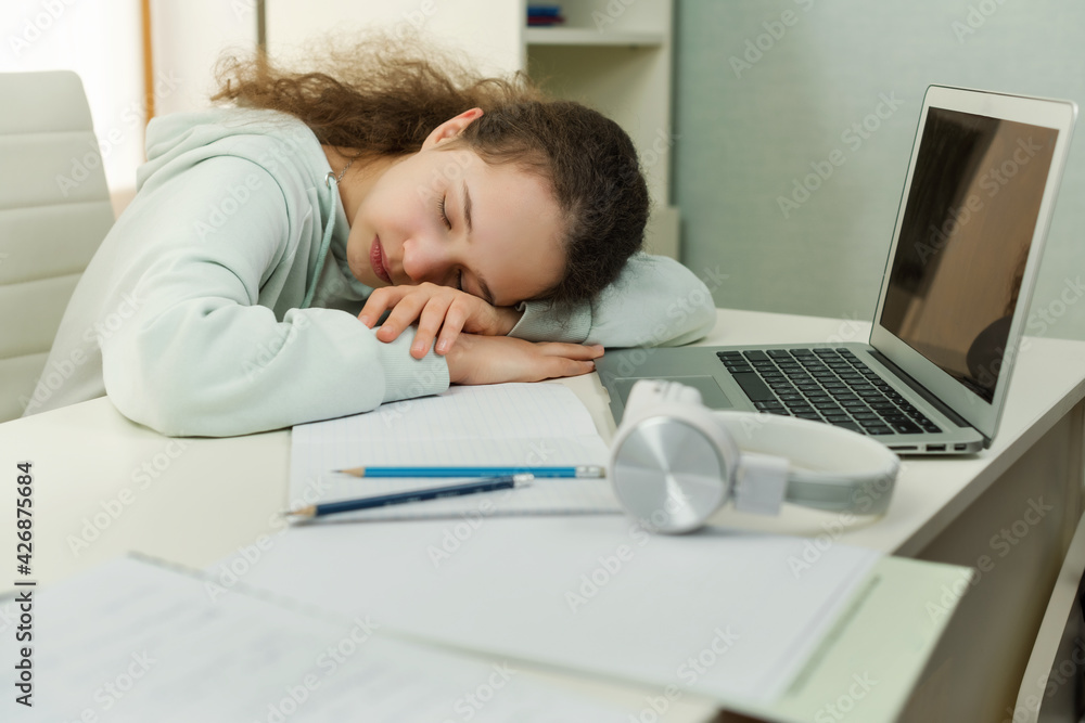 Teen girl fell asleep near the computer, she tired of learning sit at home looking at laptop. Schoolgirl frustrated about study computer work feeling uninterested demotivated. Education problem Teen girl fell asleep near the computer, she tired of learning sit at home looking at laptop. Schoolgirl frustrated about study computer work feeling uninterested demotivated. Education problem