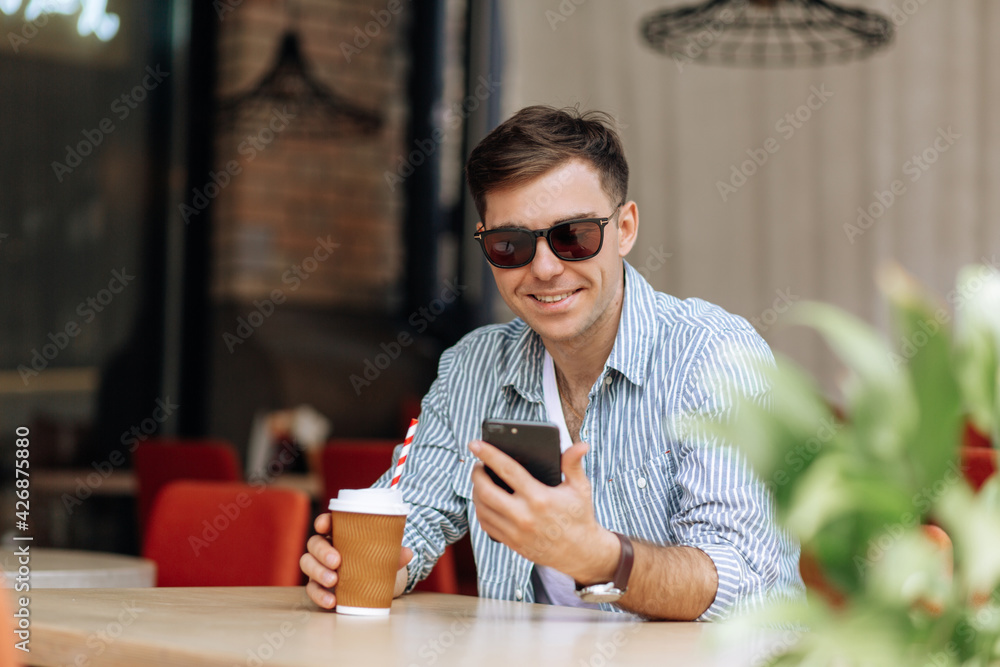 Handsome brunet man sitting in a cafe smiling and looking at the phone Handsome brunet man sitting in a cafe smiling and looking at the phone