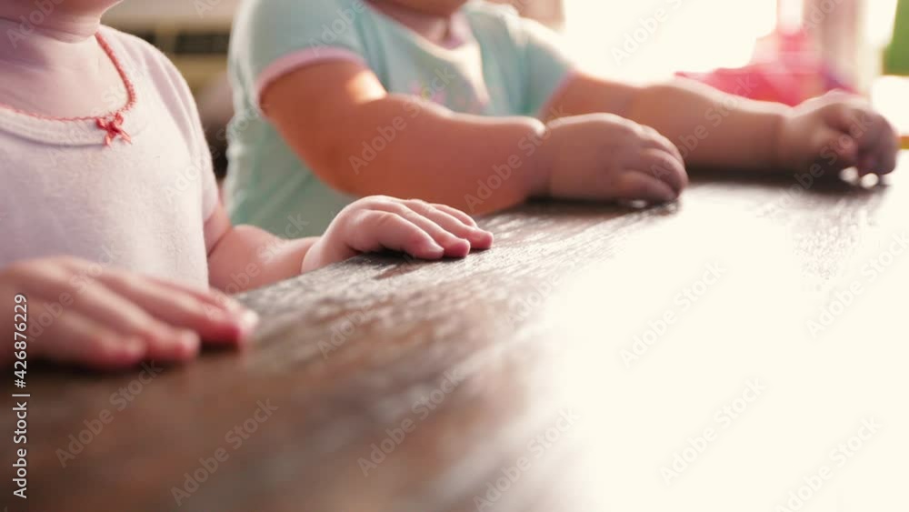 Two toddler babies standing at coffee table watching tv. Shot in 4k. Two toddler babies standing at coffee table watching tv. Shot in 4k.