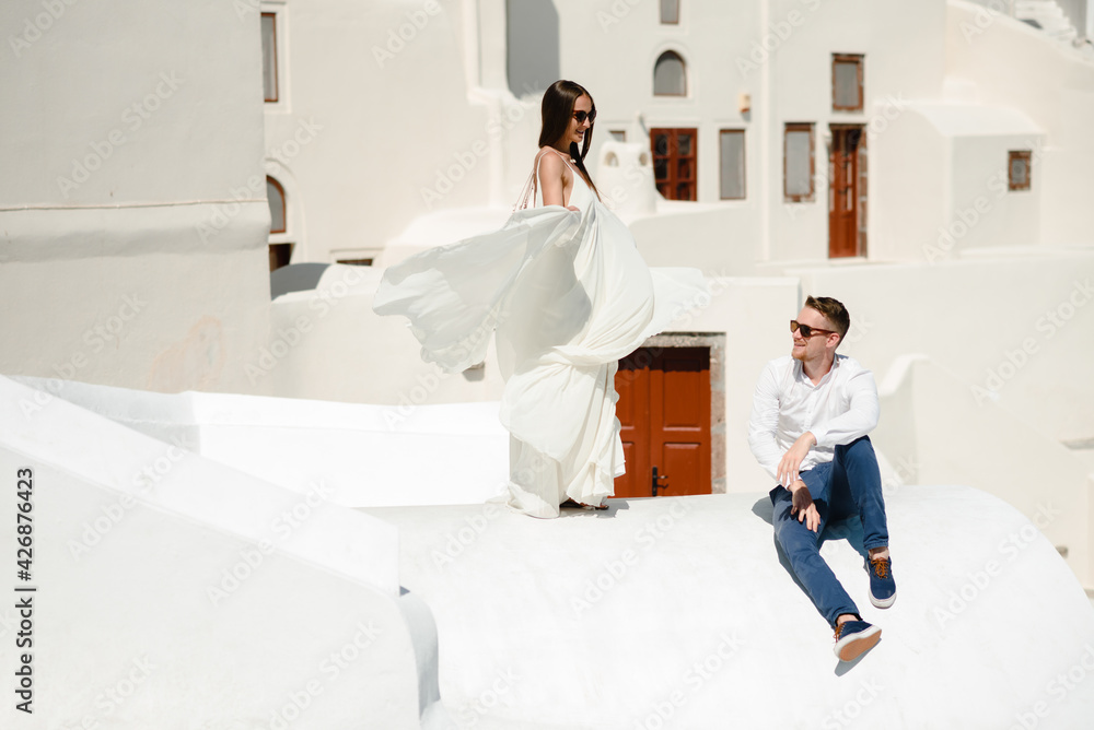 The couple is sitting on the roof in Santorini, hugging and laughing The couple is sitting on the roof in Santorini, hugging and laughing