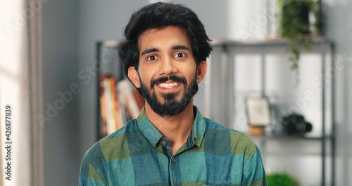Schilderij op canvas Close up portrait of happy joyful Hindu handsome man stands in room in house, looking at camera and smiling