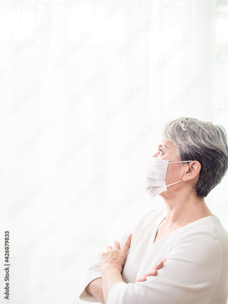 Senior asian woman wearing facemask during coronavirus and flu outbreak. Virus and illness protection, home quarantine. COVID-19. Taking on or taking off masks. Senior asian woman wearing facemask during coronavirus and flu outbreak. Virus and illness protection, home quarantine. COVID-19. Taking on or taking off masks.