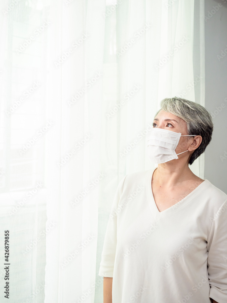 Senior asian woman wearing facemask during coronavirus and flu outbreak. Virus and illness protection, home quarantine. COVID-19. Taking on or taking off masks. Senior asian woman wearing facemask during coronavirus and flu outbreak. Virus and illness protection, home quarantine. COVID-19. Taking on or taking off masks.