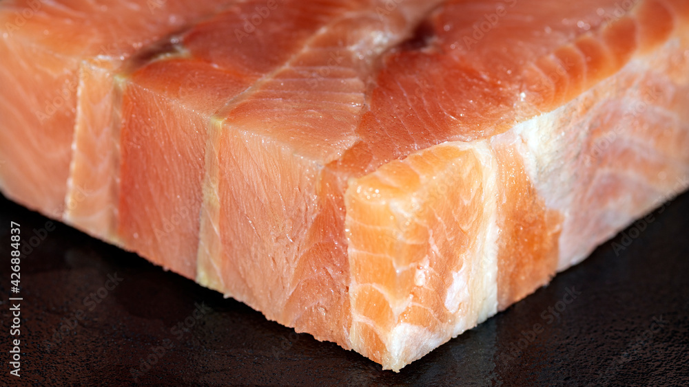 Cube piece of raw pink salmon fish on black background