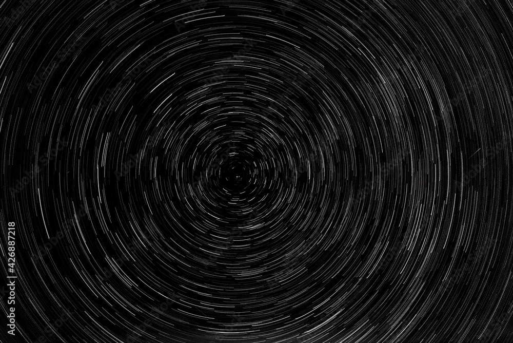 Stellar trails, the rotation of bright stars at night around the Polar Star against a blue sky and a meteor Stellar trails, the rotation of bright stars at night around the Polar Star against a blue sky and a meteor