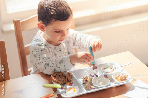 Three years old child is having a breakfast in a calm and happy mood, copy space includes