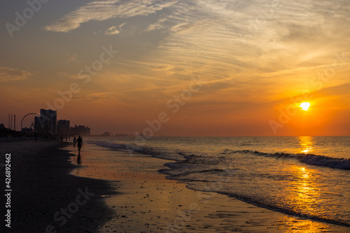 Sunrise on the beach by the ocean in a resort town. Landscape with ocean and high-rise buildings at sunset in a recreation area. Myrtle Beach, SC, USA