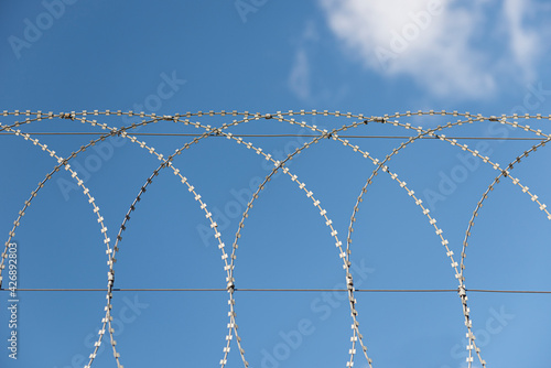 Barbed wire against a blue sky. Prison concept. Entry order. Military base.