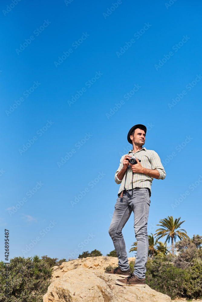 A young nature photographer takes a picture on top of a rock A young nature photographer takes a picture on top of a rock