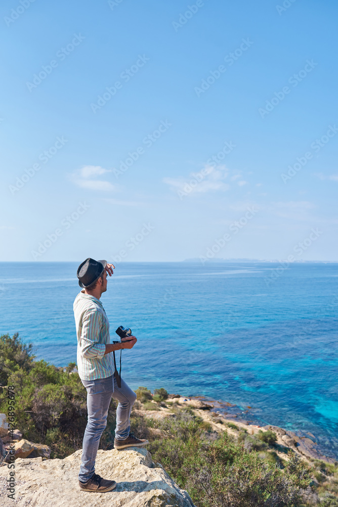 Fototapeta premium A young man holds his camera in front of a sea of beautiful blue colors