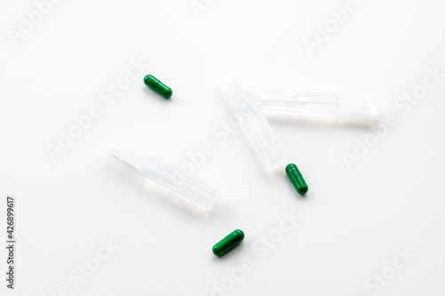 Green pills and ampoules with medicine on a white background.