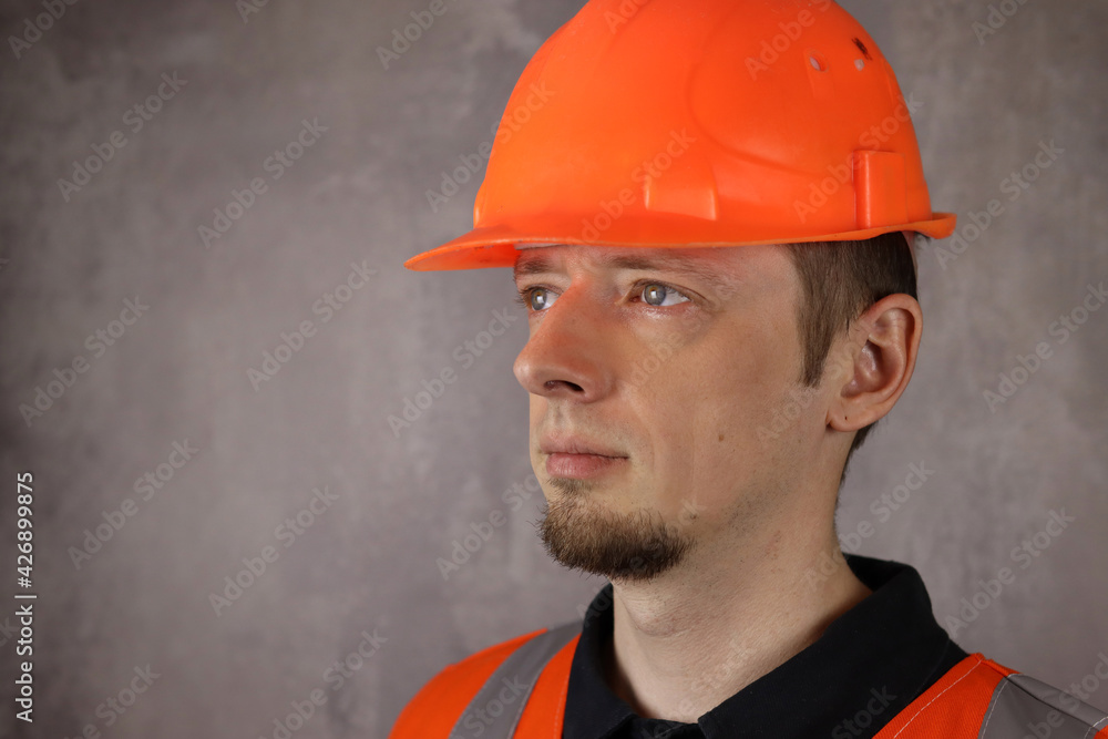 Portrait of a young handsome man worker or engineer in helmet and yellow vest on gray background. Space for text Portrait of a young handsome man worker or engineer in helmet and yellow vest on gray background. Space for text