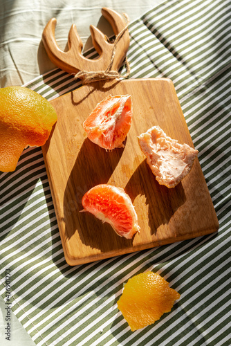 Fresh peeled grapefruit illuminated by sunlight on a wooden board