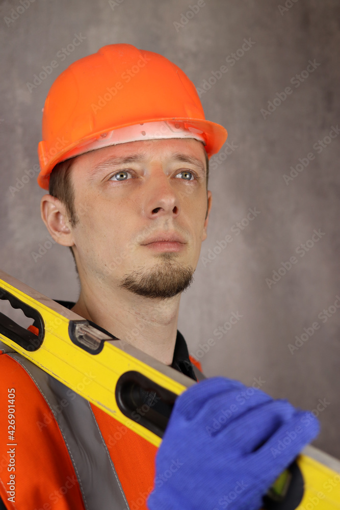 Portrait of a male engineer or builder with a construction level in hand. Vertical orientation Portrait of a male engineer or builder with a construction level in hand. Vertical orientation