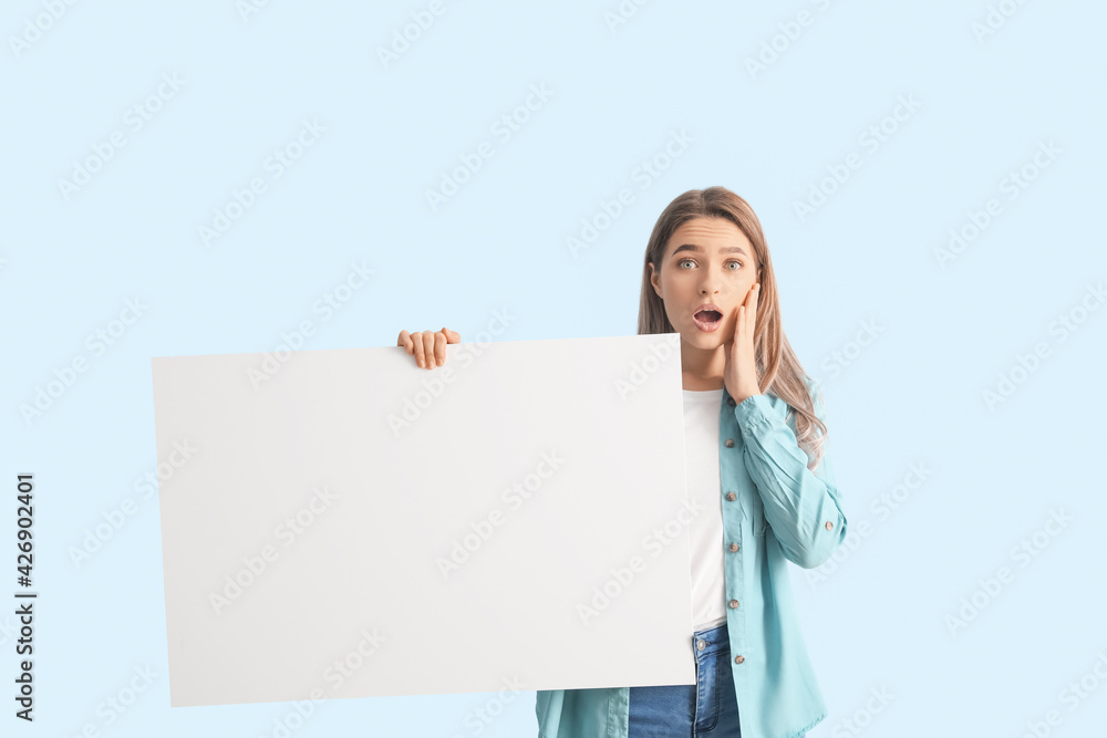 Surprised young woman with blank poster on color background Surprised young woman with blank poster on color background