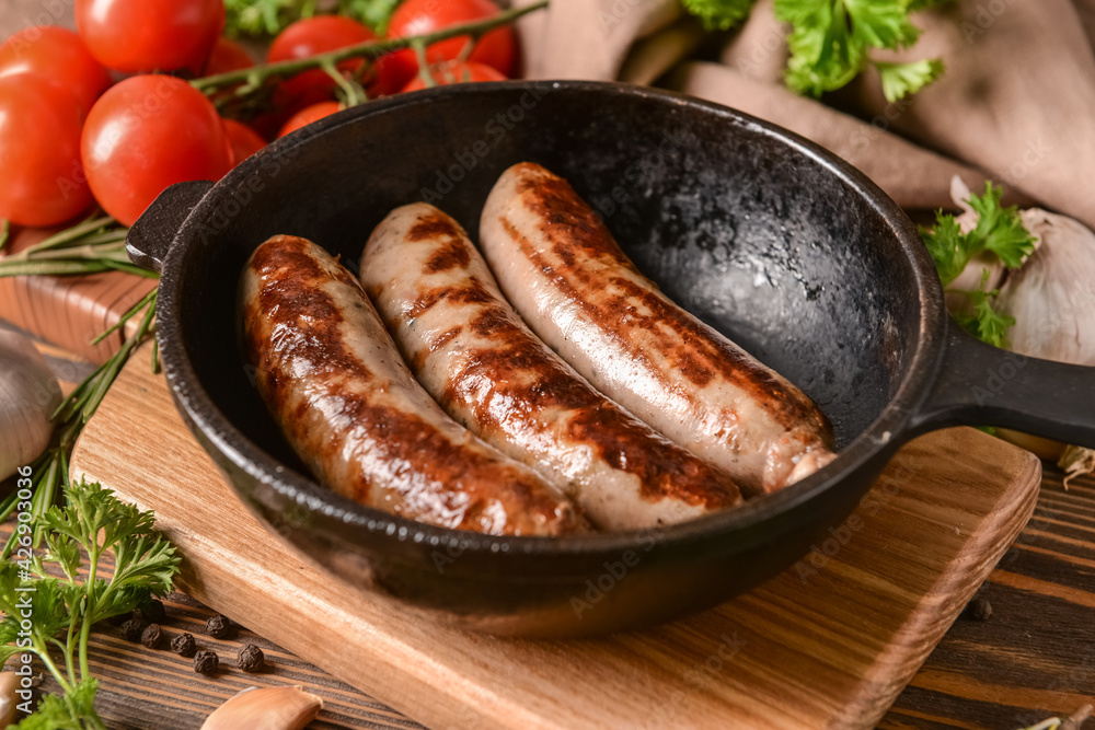 Frying pan with delicious grilled sausages on wooden background Frying pan with delicious grilled sausages on wooden background