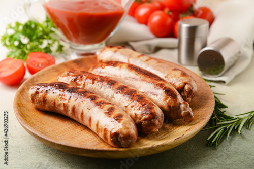 Plate with delicious grilled sausages on light background