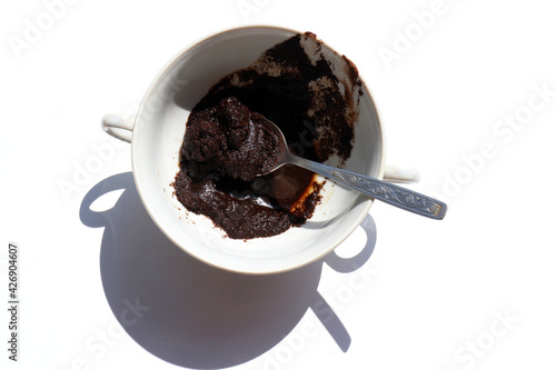Spent coffee in the cup on white background. Recycling used coffee grounds in the garden as organic compost for plant or for skin care as a coffee scrub. Zero waste concept
