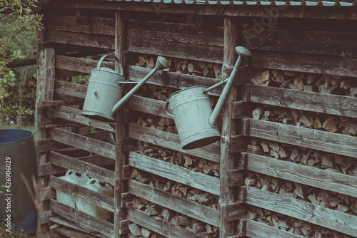 two watering cans hang on the fence