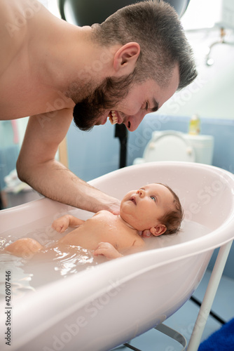beautiful baby smiles. portrait of a small child. newborn baby . daughter looks at dad and smiles. the child rejoices at the parents. baby takes a bath. A small child bathes in a small bathtub