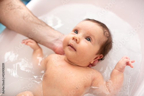 small child takes a bath. Parents bathe the baby. Pretty Baby. The newborn is bathed. Crusts on the baby's face. Bathroom with milk. The newborn is smiling. Beautiful kid portrait. little child smiles