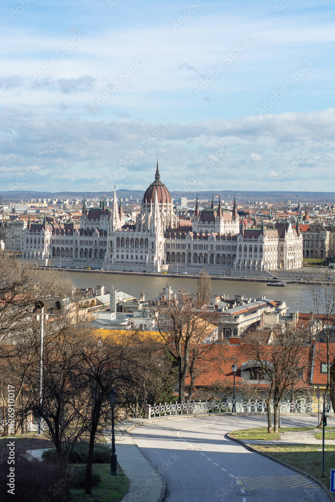 Hungarian parliament from the fisherman bastion at bright daylight with river danube and a street leading into the image at daylight