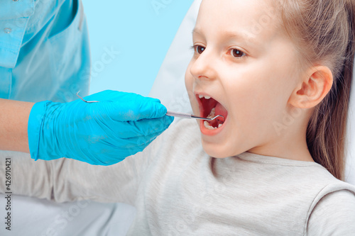 A child at a dentist's appointment. The dentist uses the tool to check the condition of the child's teeth.