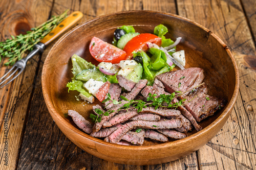 BBQ beef meat chop sirloin steak on a wooden plate with vegetable salad.  wooden background. Top view