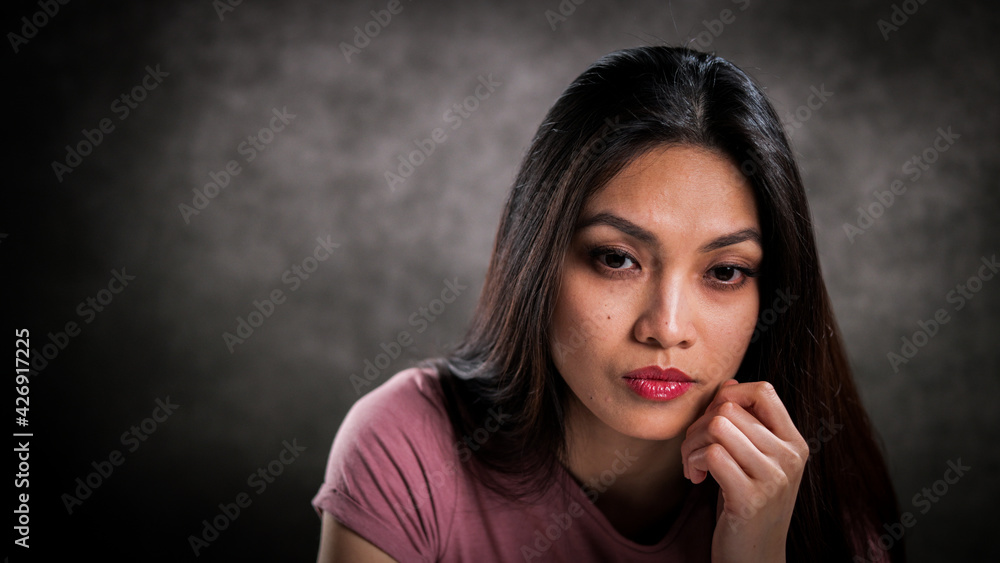 Close-up of a young woman with a thoughtful facial expression - studio photography Close-up of a young woman with a thoughtful facial expression - studio photography