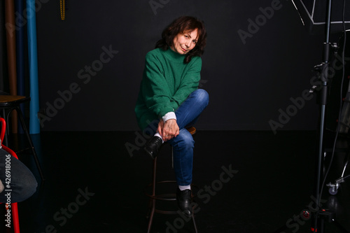 Adult brunette woman in a green sweater in the studio. Beautiful Model Age. Modern fashion for appearance. Copy space