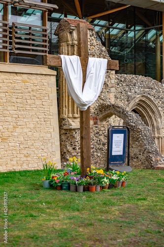 Fototapeta Wooden cross with a white shroud surrounded by flowers in Cathedral Close in the