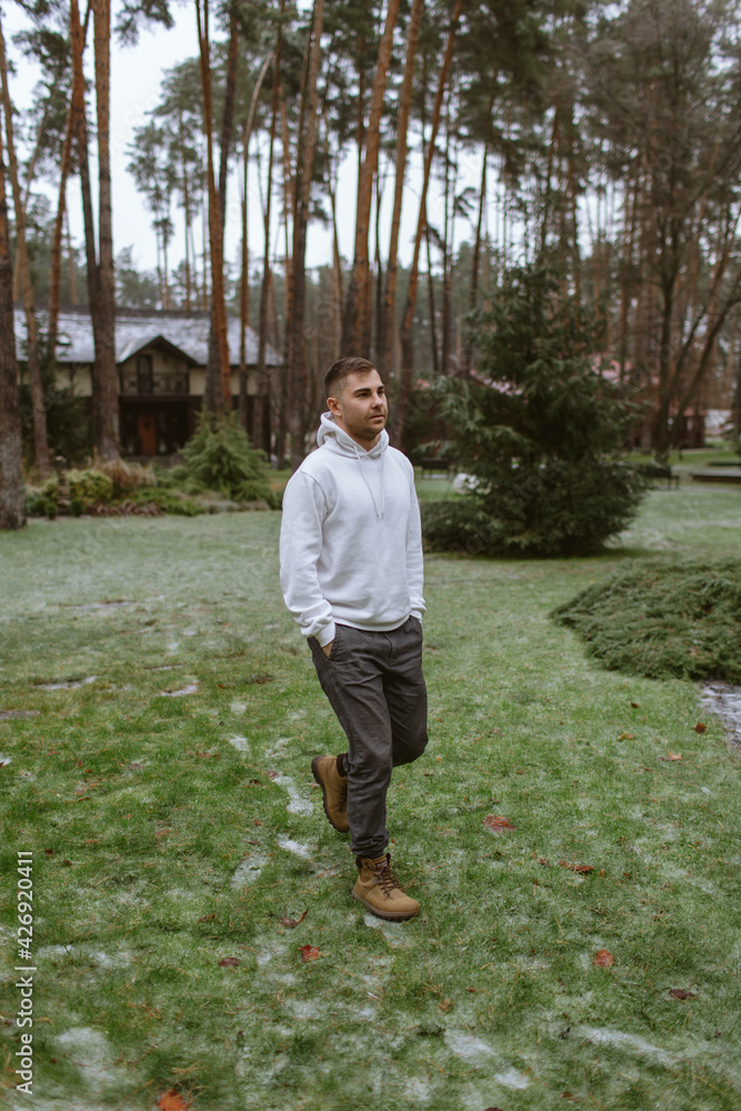 Young man walks through the woods in a white hoodie Young man walks through the woods in a white hoodie