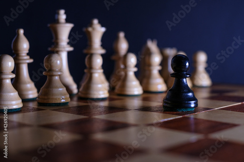 a black pawn is alone in front of the white pieces on the chessboard