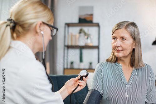 Close up photo of blood pressure measurement. blurred view of female nurse or doctor doing blood pressure monitoring for senior woman at home. Hypertension and heart deseases.