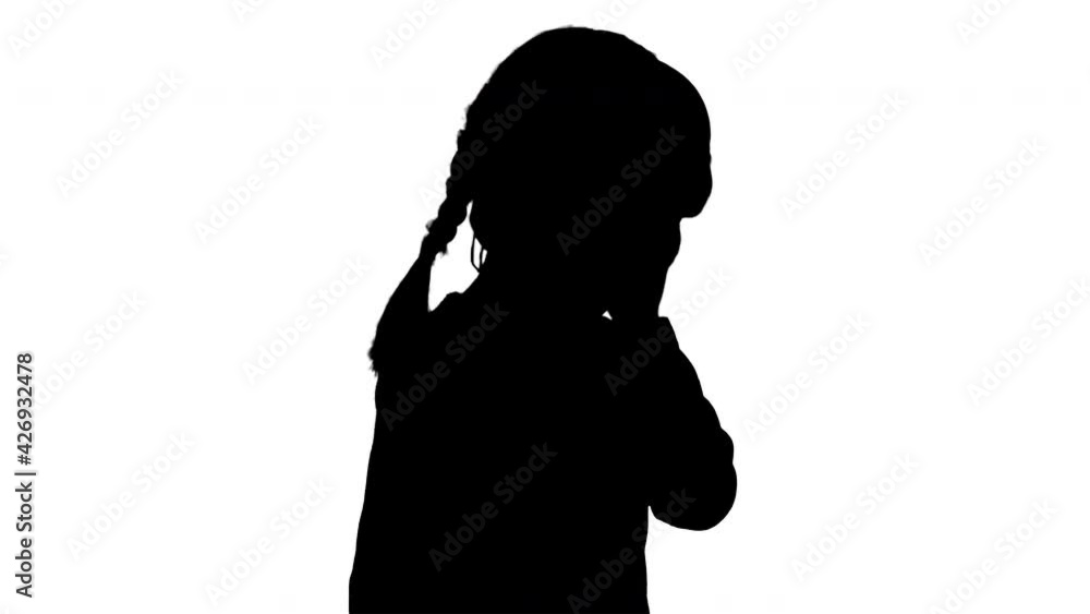Silhouette Cute girl dressed in white holding headphones with one hand and nodding her head to the music while walking. Silhouette Cute girl dressed in white holding headphones with one hand and nodding her head to the music while walking.