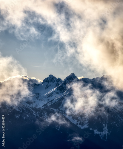 Rugged Mountain Peaks Covered in Snow and Clouds in Canadian Nature Landscape. Taken in Squamish, North of Vancouver, British Columbia, Canada.