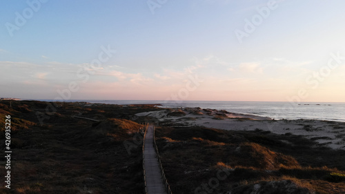 Aerial view of the Northern Litoral Natural Park in Ofir  Esposende  Portugal. Wooden boardwalk  sea  beach boulders and waves at sunset.